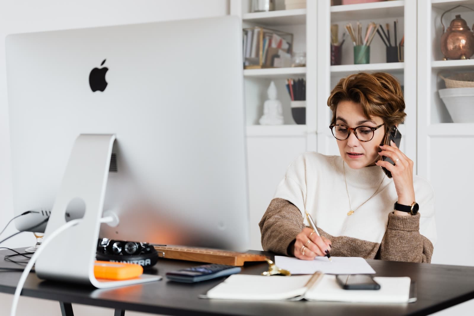 An independent salesperson on a call at her home office desk